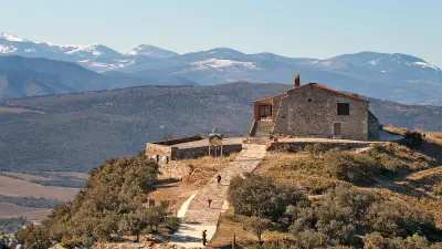 El eremitorio de Força Réal, encaramado en su espolón rocoso frente a los Pirineos nevados